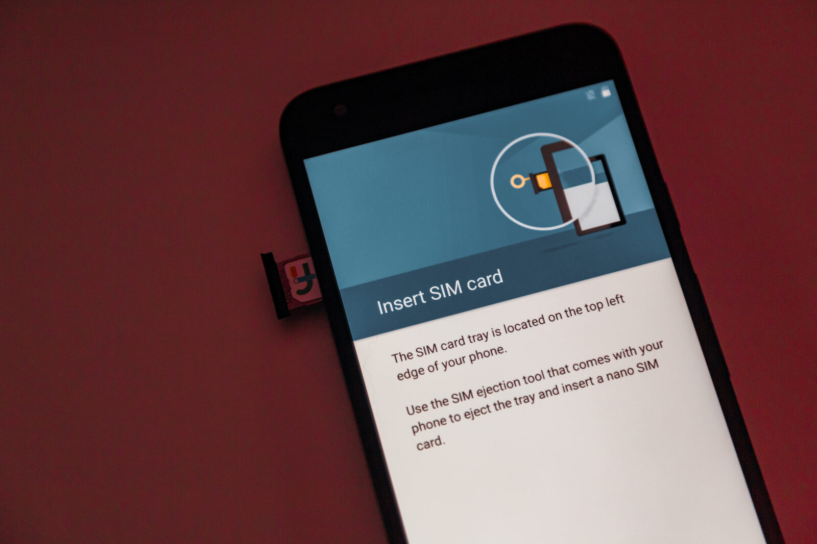 Smartphone mit geöffnetem SIM-Karten-Schacht, auf dem Bildschirm die Aufforderung, eine SIM-Karte einzulegen